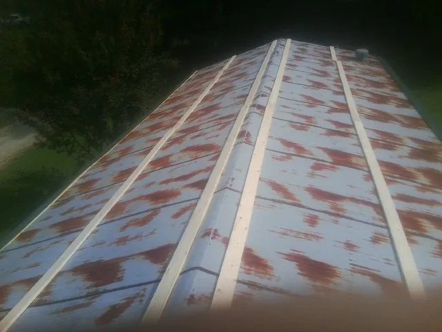 Rusted metal roof panels with new wood purlins before replacement — Storm Damage Roof Repair in Oakes by Roofing Brothers