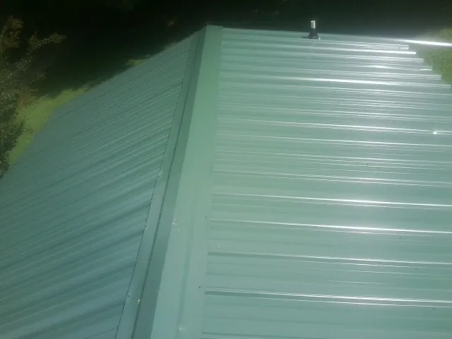 New green metal panels meeting at the ridge of a roof — Flat Roof Repair work by our crew in Oakes