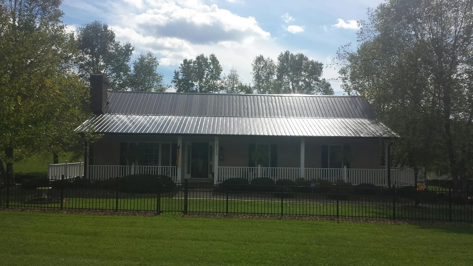 Gray metal roof on a brick ranch with a full width front porch — Gutter Guard Installation work by our crew in Oakes