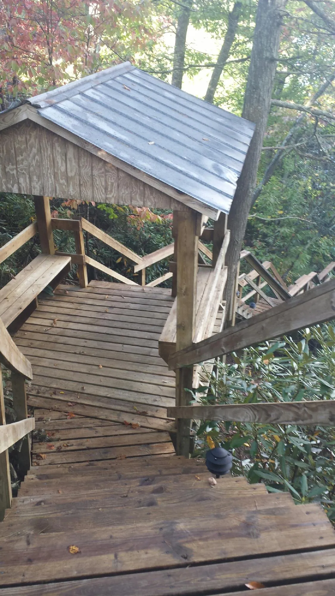 Metal roofed shelter over wooden steps on a wooded walkway — Skylight Repair & Installation work by our crew in Oakes