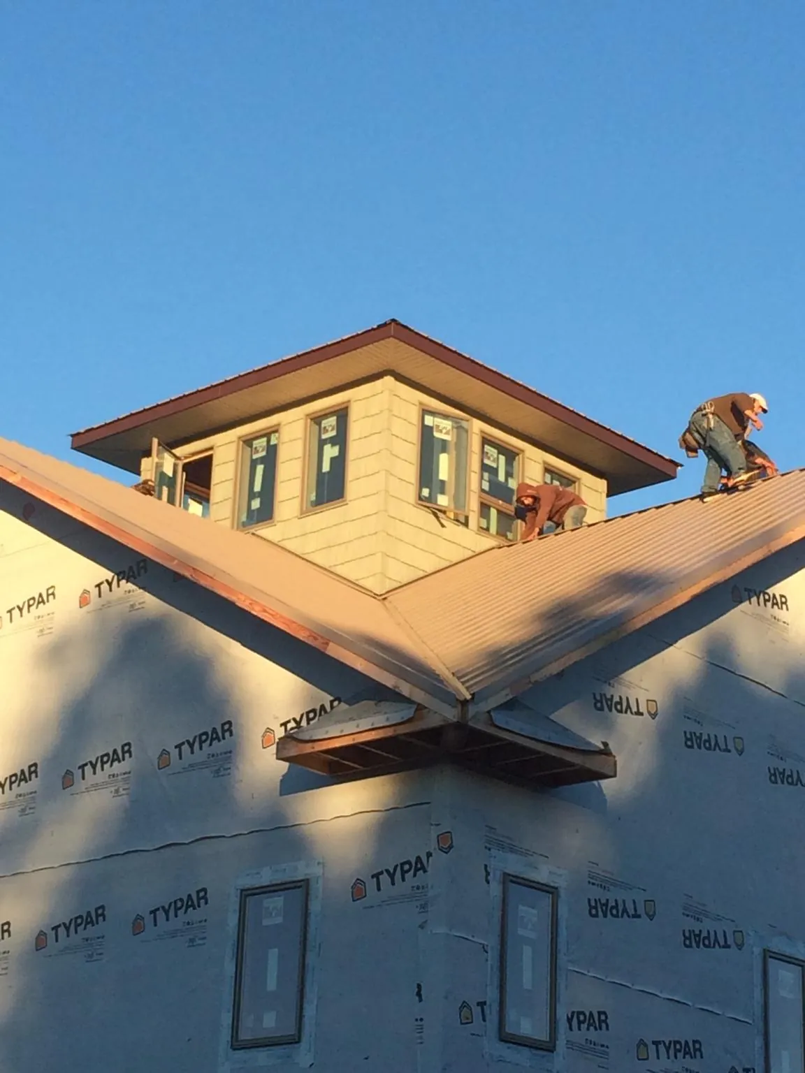 Roofers working around a rooftop cupola on a new metal roof at sunset — Roof Waterproofing in Oakes by Roofing Brothers